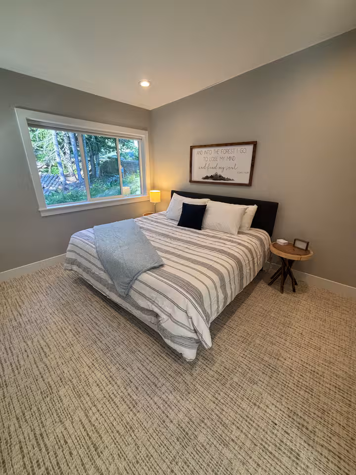 Guest bedroom with a queen bed and forest view